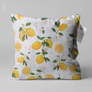 Puede incluir: Almohada blanca con un patrón de limón y flores. La almohada tiene un fondo blanco con limones amarillos y flores blancas. La almohada está hecha de una tela suave y cómoda.
