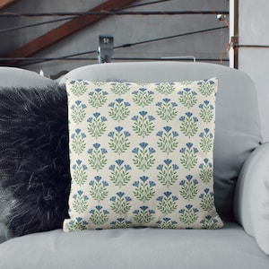 Blue botanical pattern cushion styled on a grey sofa next to a black faux fur pillow for a modern, cozy home decor look.