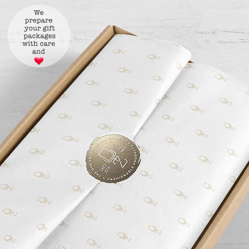 May include: A white tissue paper with a gold foil logo that says "The Oya Project, Since 2018, Fashionable Products". The logo is a circle with a stylized "DN" inside.