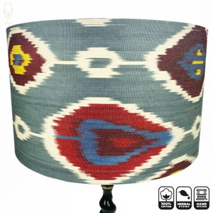 May include: A blue and red patterned lampshade with a black wooden base. The lampshade is made of 100% cotton and is handwoven. The fabric is herbally dyed.