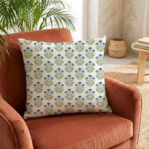 Soft blue wildflower chenille pillow on a terracotta accent chair, showing the vibrant contrast of botanical patterns against warm tones.