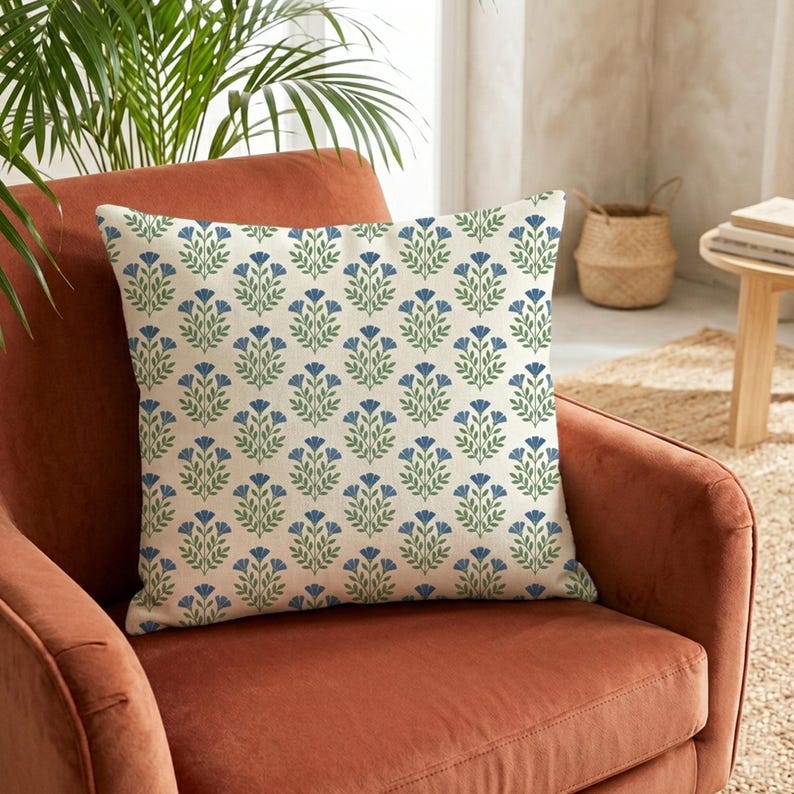 Soft blue wildflower chenille pillow on a terracotta accent chair, showing the vibrant contrast of botanical patterns against warm tones.