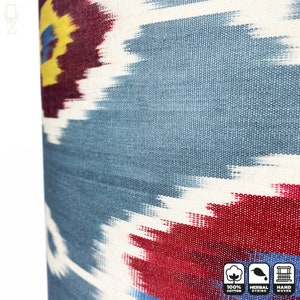 May include: Close-up of a blue, red, white, and yellow ikat fabric. The fabric is hand-woven and features a traditional ikat pattern. The fabric is 100% cotton and is dyed with natural herbs.