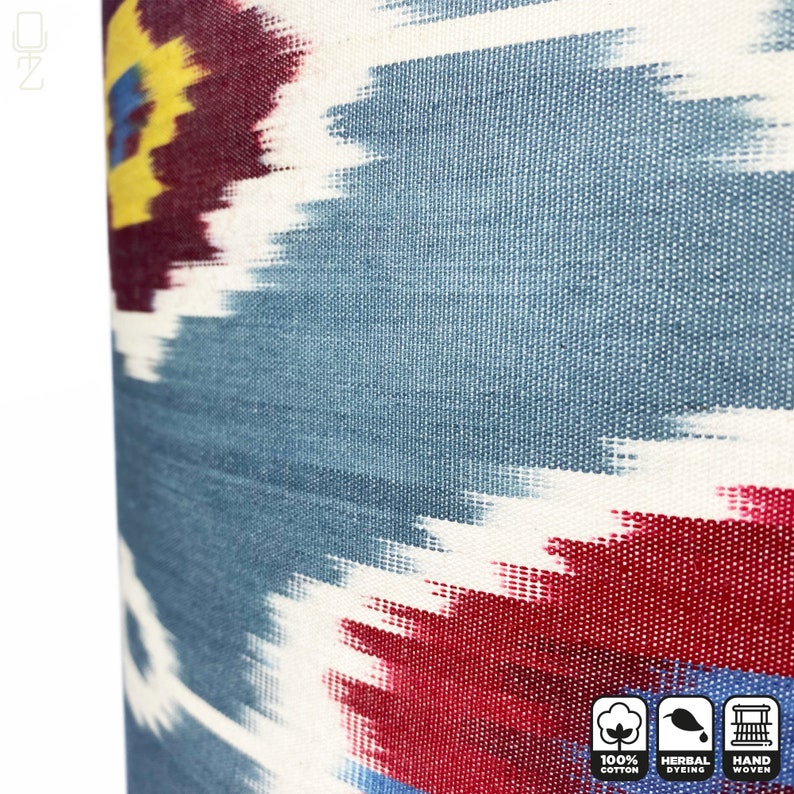 May include: Close-up of a blue, red, white, and yellow ikat fabric. The fabric is hand-woven and features a traditional ikat pattern. The fabric is 100% cotton and is dyed with natural herbs.