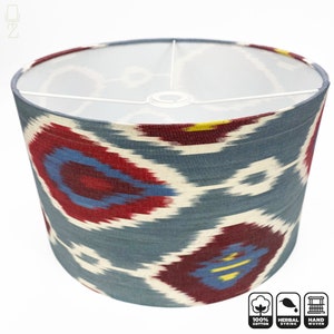 May include: A cylindrical lampshade with a blue, red, and white ikat pattern. The lampshade is made of 100% cotton and is handwoven. It is also herbally dyed.