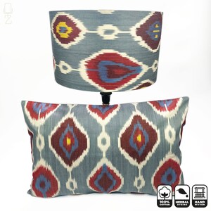 May include: A blue and red patterned lampshade and pillow made of 100% cotton with a handwoven design. The fabric is dyed with natural herbs. The lampshade is cylindrical and the pillow is rectangular.