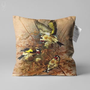 Op de afbeelding: Een decoratief kussen met een bruine achtergrond met een gedetailleerde illustratie van drie gele vogels met zwarte en rode markeringen die op takken met groene bladeren zitten.