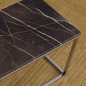 Puede incluir: Mesa de centro rectangular con tapa de mármol negro con vetas blancas. La mesa tiene una estructura de cromo pulido. La mesa mide aproximadamente 122 cm de largo, 61 cm de ancho y 41 cm de alto.