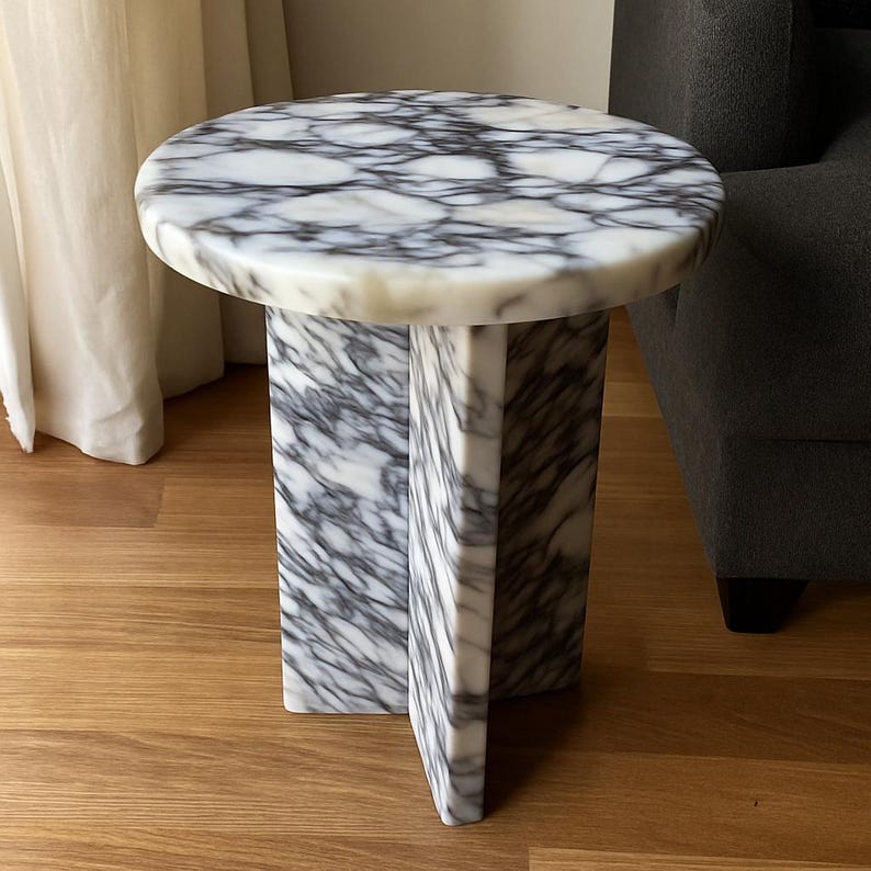 May include: A round marble side table with a white and gray veined pattern. The table has a circular top and a geometric base. The table is approximately 20 inches in height.