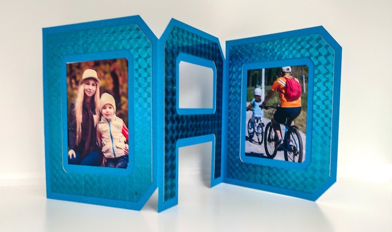 May include: A blue card with the word "DAD" spelled out in large letters. Each letter has a photo frame inside. The photo frames contain pictures of a family.