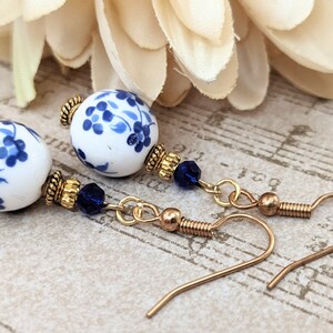 May include: A pair of blue and white porcelain bead earrings with gold accents and blue crystal beads hanging from gold chains.