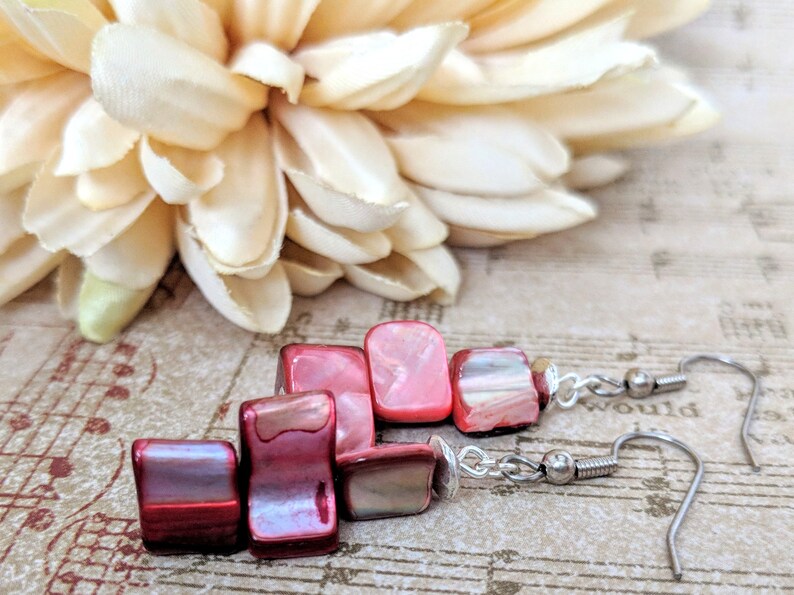 May include: A pair of dangle earrings with red and pink shell beads and silver hooks.