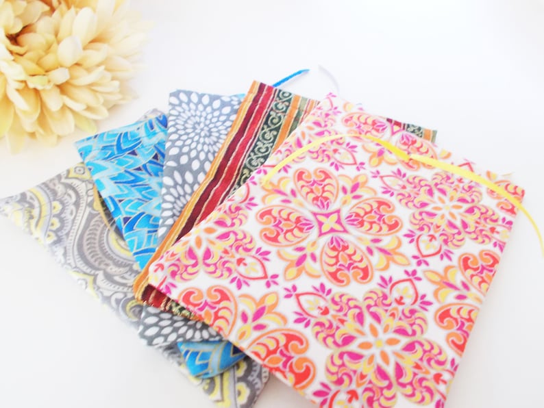 May include: Five fabric pouches with different colorful patterns. The pouches are made of cotton and have a drawstring closure. The pouches are stacked on top of each other.