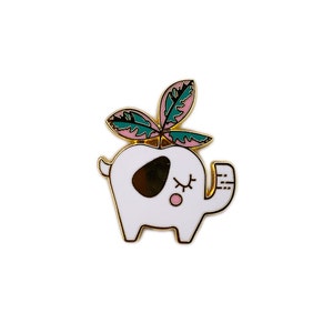 May include: A white enamel pin of an elephant with a pink and green plant growing out of its head. The elephant has black eyes and a pink nose.