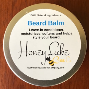 May include: A silver tin with a white label that reads "100% Natural Ingredients Beard Balm Leave-in conditioner, moisturizes, softens and helps style your beard. Honey Lake Bee Co. www.HoneyLakeBeeCompany.com". The label also features a cartoon bee.