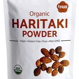 May include: White pouch of organic Haritaki powder. The package features the text "Organic HARITAKI POWDER" and "Vegan • Gluten-Free • Pure • Non-GMO." The pouch also displays the USDA Organic seal and contains 113 g of product.