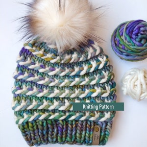 Può includere: Un cappello a maglia con un pon pon bianco e un filato multicolore con strisce bianche. Il cappello ha un'etichetta in pelle che dice "Little Loops". Modello di maglia.