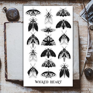 May include: A sheet of stickers featuring 16 black and white moth illustrations with intricate details. The stickers are arranged in four rows of four. The text "WICKED HEART" is printed at the bottom of the sheet.