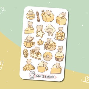 Op de afbeelding: Een stickervel met illustraties van beren en desserts. De ontwerpen omvatten een pompoen, cake, pannenkoeken en een croissant. Het kleurenpalet is voornamelijk beige en lichtbruin, met witte en gele accenten. De tekst "magical blossom" staat onderaan.