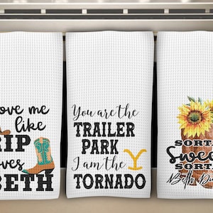 May include: Three white waffle-weave kitchen towels with country-themed designs. One towel reads "Love me like RIP loves BETH" with a cowboy hat and boots. Another says "You are the TRAILER PARK I am the TORNADO". The third towel features a sunflower and reads "SORTA Sweet SORTA Beth Dutton".