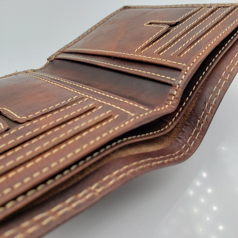 May include: A brown leather wallet with multiple card slots and a billfold. The wallet has a stitched design with brown thread.