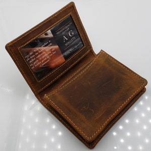 May include: A brown leather wallet with a clear plastic window on the front. The window displays a business card with the text "Premium Quality Leather AG Wallets Quality Meets Affordability".