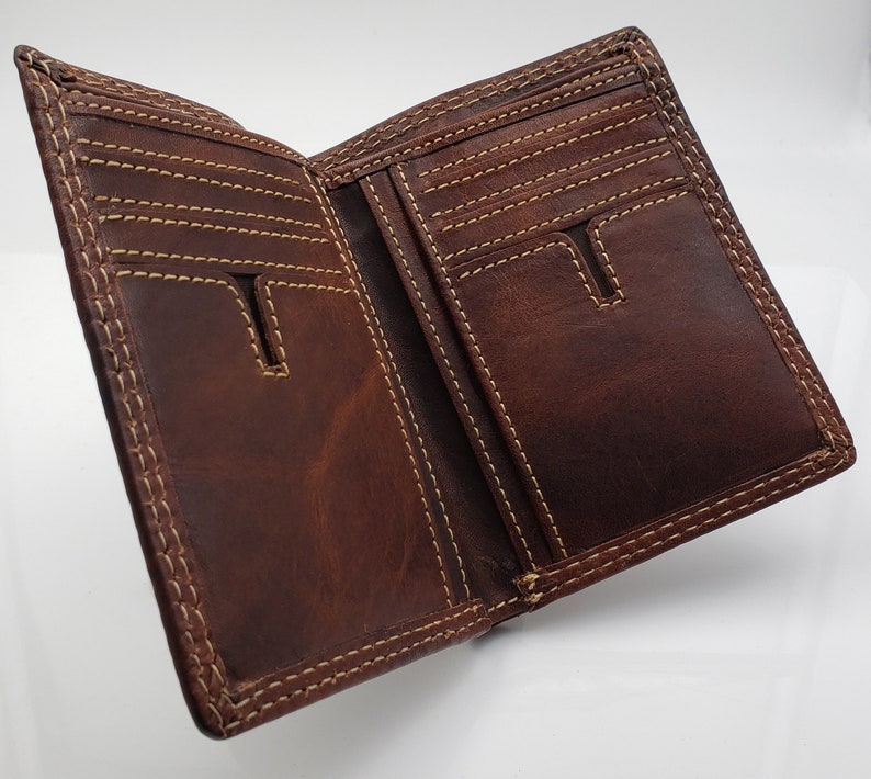 May include: A brown leather wallet with multiple card slots and a billfold. The wallet has a stitched edge and is open to show the interior.