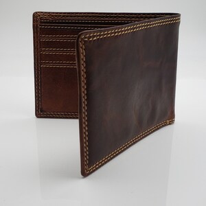 May include: A brown leather wallet with a stitched edge and multiple card slots. The wallet is open and folded in half.