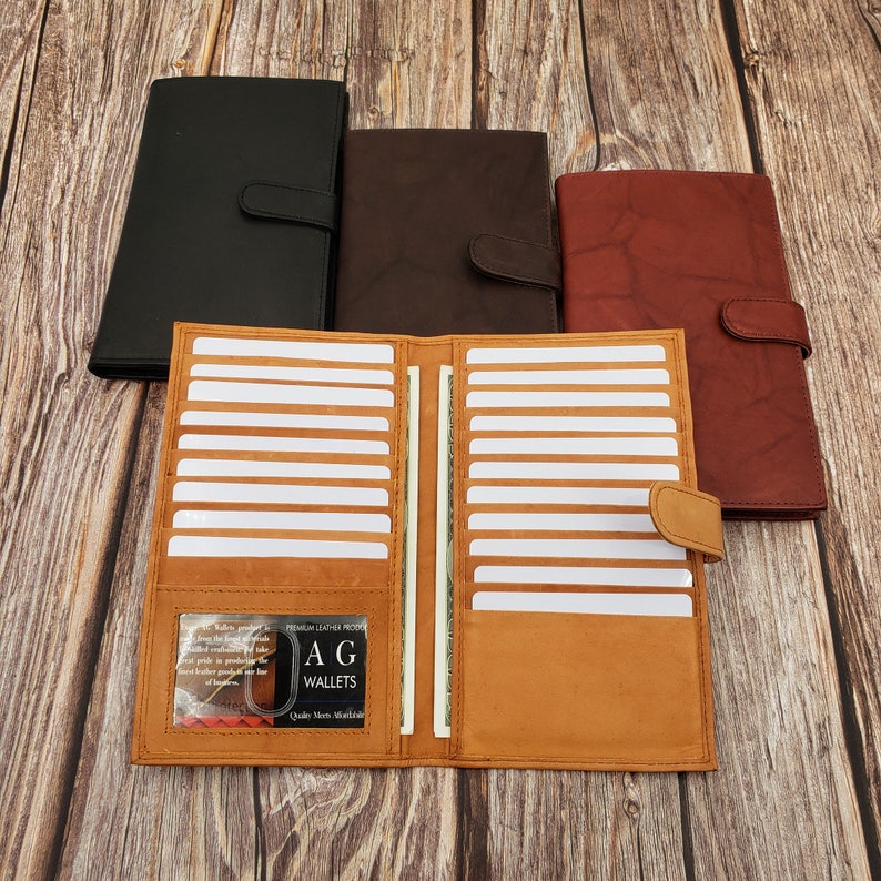 Peut inclure: Un portefeuille en cuir marron avec de multiples fentes pour cartes et un porte-billets. Le portefeuille est ouvert et l'int&eacute;rieur est visible. Le portefeuille porte une &eacute;tiquette indiquant "A.G. Wallets Quality Made Worldwide".