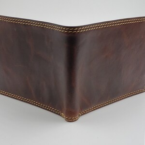 May include: A brown leather wallet with a stitched edge.