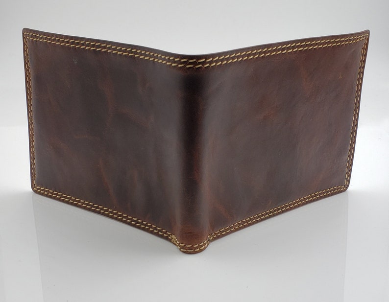 May include: A brown leather wallet with a stitched edge.