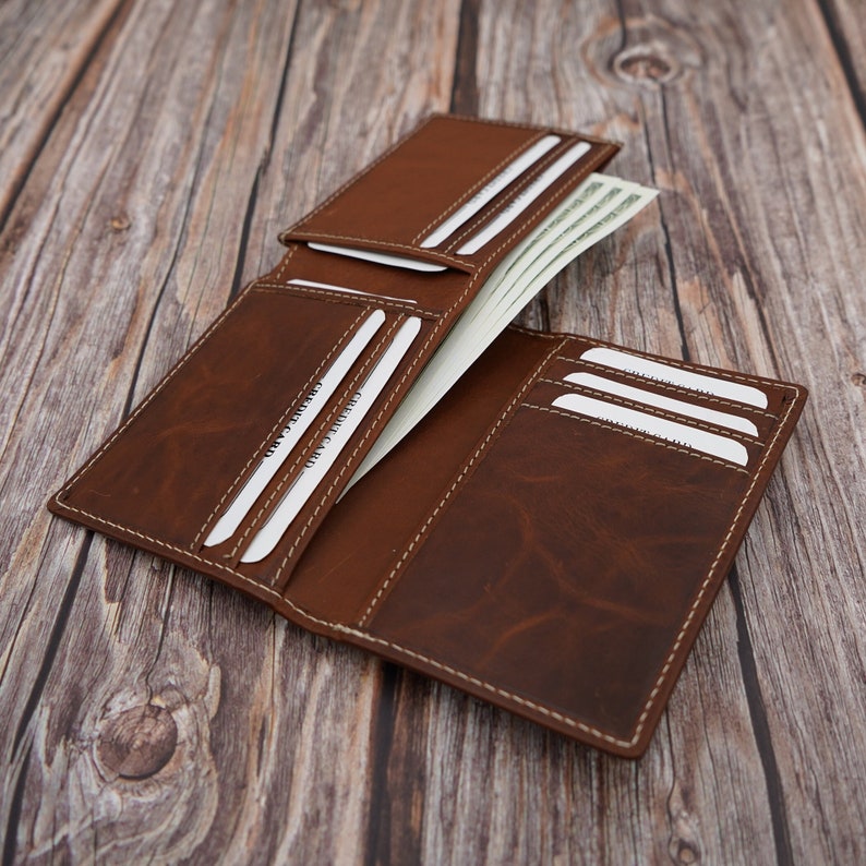 May include: A brown leather wallet with multiple card slots and a billfold. The wallet is open and has cash inside.