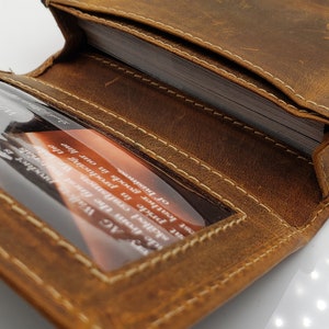May include: A brown leather card holder with a stitched edge and a clear plastic window for displaying a business card. The card holder is open and shows the interior with multiple card slots.