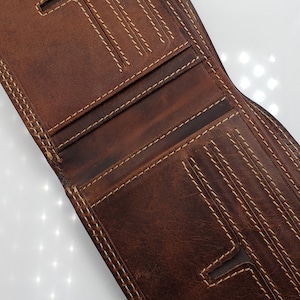 May include: A brown leather wallet with multiple card slots and a billfold. The wallet has a stitched design with light brown thread.
