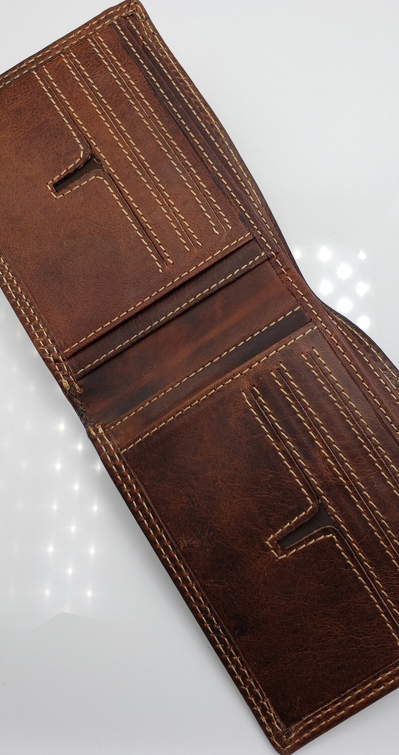 May include: A brown leather wallet with multiple card slots and a billfold. The wallet has a stitched design with light brown thread.