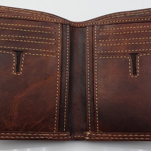 May include: A brown leather wallet with multiple card slots and a billfold. The wallet is open and the interior is visible.
