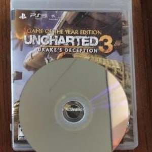 K&ouml;nnte beinhalten: Eine PlayStation 3-Spieledisk f&uuml;r Uncharted 3: Drake's Deception, Game of the Year Edition. Die Disc befindet sich in einem durchsichtigen Plastikcase mit einem schwarzen Etikett.
