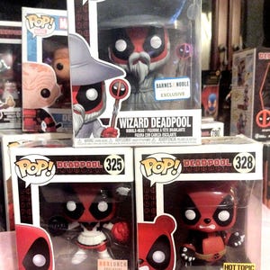 Puede incluir: Varias figuras Funko Pop! de Deadpool en varios disfraces, incluyendo las versiones Wizard, Cheerleader y Panda. Cada figura está en su caja original, con el logo Pop! y el nombre del personaje visibles.