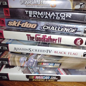 K&ouml;nnte beinhalten: Ein Stapel von zehn PlayStation 3-Videospielh&uuml;llen. Die Spiele beinhalten Uncharted: Drakes Deception, Terminator Salvation, Ski-Doo Snowmobile Challenge, The Godfather II, Assassin's Creed IV: Black Flag, NASCAR 2011 und NASCAR The Game: Inside Line.