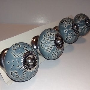 May include: Four gray ceramic cabinet knobs with silver accents and a floral design.