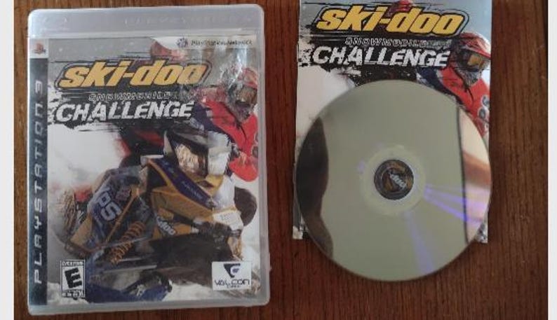 K&ouml;nnte beinhalten: Ein PlayStation 3-Spielecase f&uuml;r Ski-Doo Snowmobile Challenge. Das Cover zeigt ein gelbes und schwarzes Schneemobil mit einem Fahrer in einem roten und schwarzen Anzug. Das Spiel ist f&uuml;r alle Altersgruppen freigegeben (E).