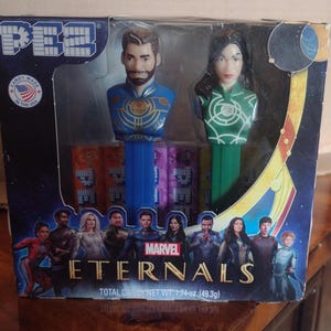 Puede incluir: Un juego de dispensadores PEZ en caja con dos cabezas de personajes de la pel&iacute;cula Marvel Eternals. La caja tiene un dise&ntilde;o azul y dorado con el t&iacute;tulo de la pel&iacute;cula e im&aacute;genes de personajes. El juego incluye caramelos y est&aacute; hecho en EE. UU.