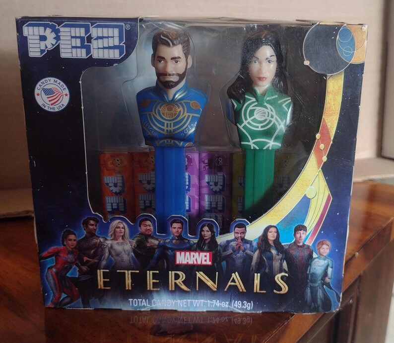 Puede incluir: Un juego de dispensadores PEZ en caja con dos cabezas de personajes de la pel&iacute;cula Marvel Eternals. La caja tiene un dise&ntilde;o azul y dorado con el t&iacute;tulo de la pel&iacute;cula e im&aacute;genes de personajes. El juego incluye caramelos y est&aacute; hecho en EE. UU.