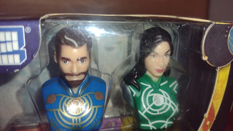 Puede incluir: Dos dispensadores de PEZ con bustos de personajes. Uno tiene un uniforme azul con detalles dorados y barba marr&oacute;n. El otro tiene un uniforme verde con detalles blancos y cabello negro. El embalaje es visible.