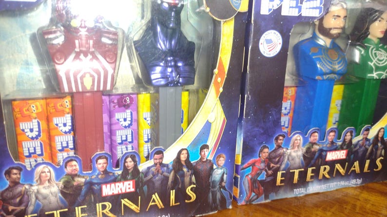 Puede incluir: Dispensadores de PEZ de Marvel Eternals en embalaje. Los dispensadores presentan cabezas de personajes en azul, verde y morado. El embalaje tiene un fondo azul oscuro con im&aacute;genes de personajes y el logotipo de Marvel Eternals. Fabricado en EE. UU.