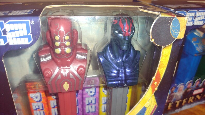 Puede incluir: Un juego empaquetado de dispensadores PEZ con personajes de la pel&iacute;cula Marvel Eternals. Los dispensadores incluyen figuras rojas y azules con dise&ntilde;os detallados y paquetes de caramelos coloridos.