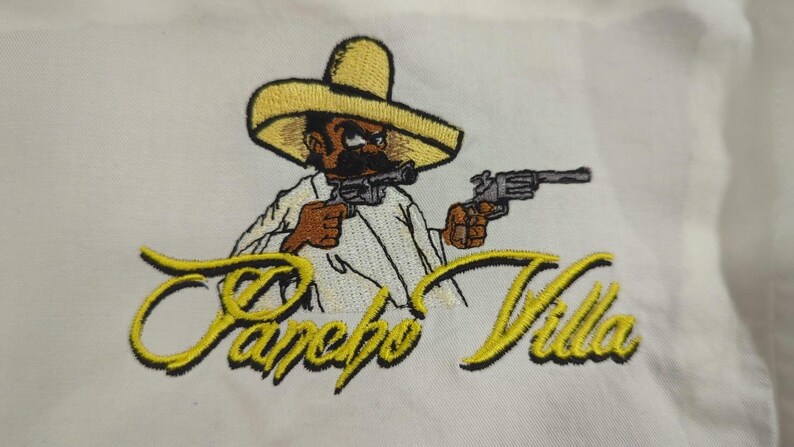 Pu&ograve; includere: Una toppa ricamata su tessuto bianco raffigurante un personaggio dei cartoni animati con un sombrero giallo che impugna due revolver grigi. Sotto il personaggio, il testo Pancho Villa &egrave; ricamato in corsivo giallo con contorno nero.
