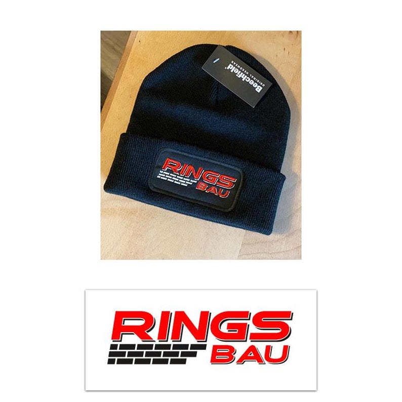Pu&ograve; includere: Un berretto in maglia nero con risvolto e una toppa rettangolare. La toppa mostra la scritta RINGS BAU in rosso e bianco con una grafica a mattoni neri. Un'etichetta nera del marchio Beechfield &egrave; attaccata alla parte superiore del berretto.