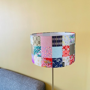 Op de afbeelding: Een lampenkap met een patchwork-ontwerp met verschillende kleurrijke stoffen met bloemen- en geometrische patronen.