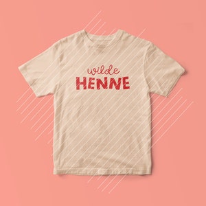以下が含まれることがあります： 赤い文字で「wilde HENNE」とプリントされたベージュのTシャツです。